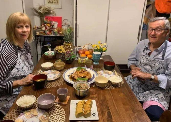 Two guests sit in front of their handmade Japanese home cooking.